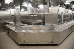 "Stainless steel modern commercial kitchen. Plate collection and return area with cupboards, shelves and racks."